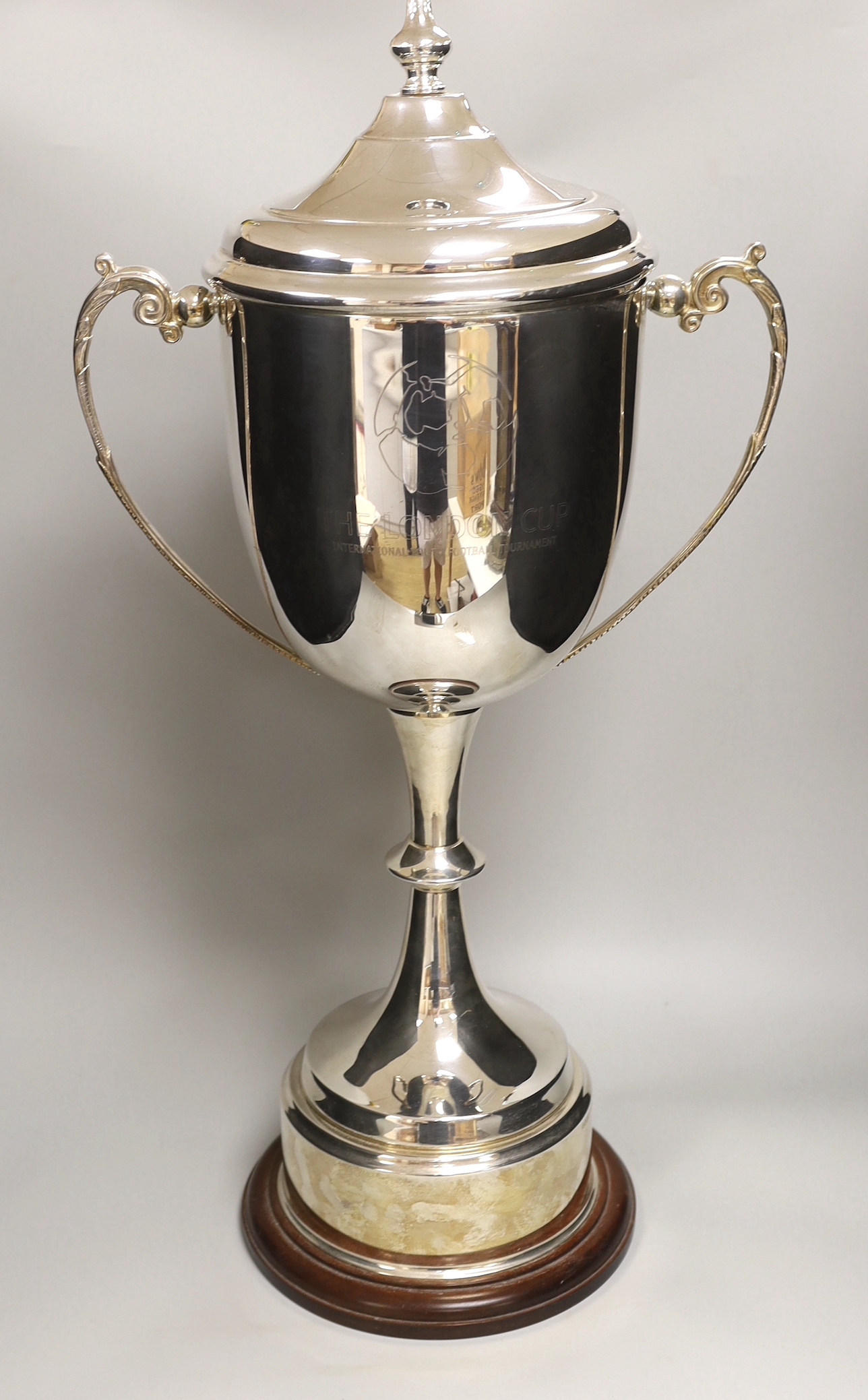‘The London Cup’, a large silver plated twin handled trophy and cover on circular wooden stand, 70cm high